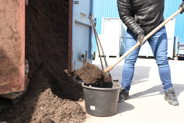 človek naberá kompost lopatou